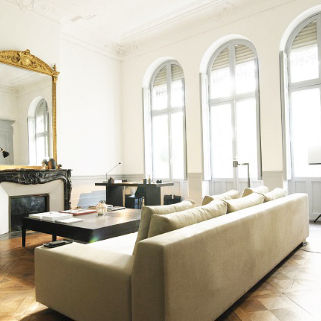Salon d'un appartement toulousain rénové avec canapé et grandes fenêtres